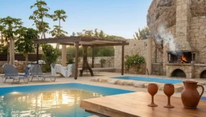 Spilies Tavern at Coral Bay with a stone outdoor grill beside a swimming pool and sun loungers in a Mediterranean villa setting