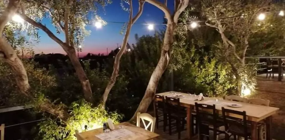 A cozy outdoor seating area at Solos - Kebab House & Beer Garden, featuring tables, umbrellas, and string lights at dusk.