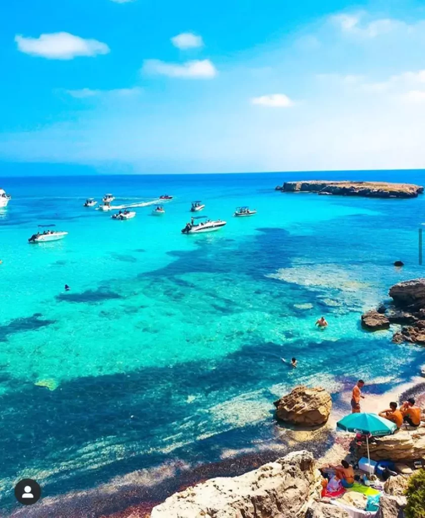 Crystal-clear turquoise waters of the Blue Lagoon in Akamas, Cyprus, surrounded by rocky cliffs and lush greenery.